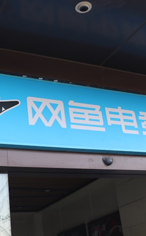 A building entrance features a vibrant blue sign with white Chinese characters and a stylized orca logo in black and white. The overall appearance suggests an establishment focused on eSports or digital activities.
